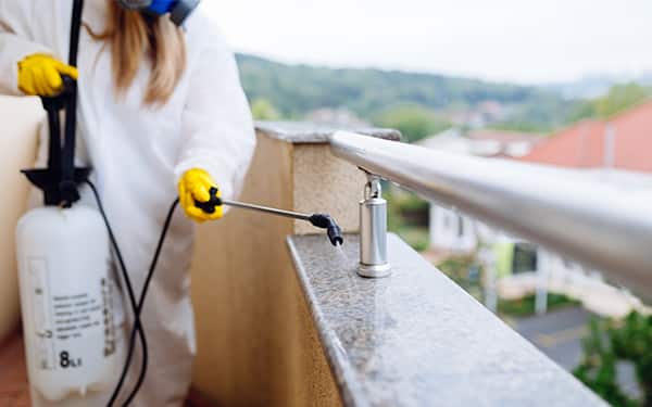 pest control professional spraying a balcony
